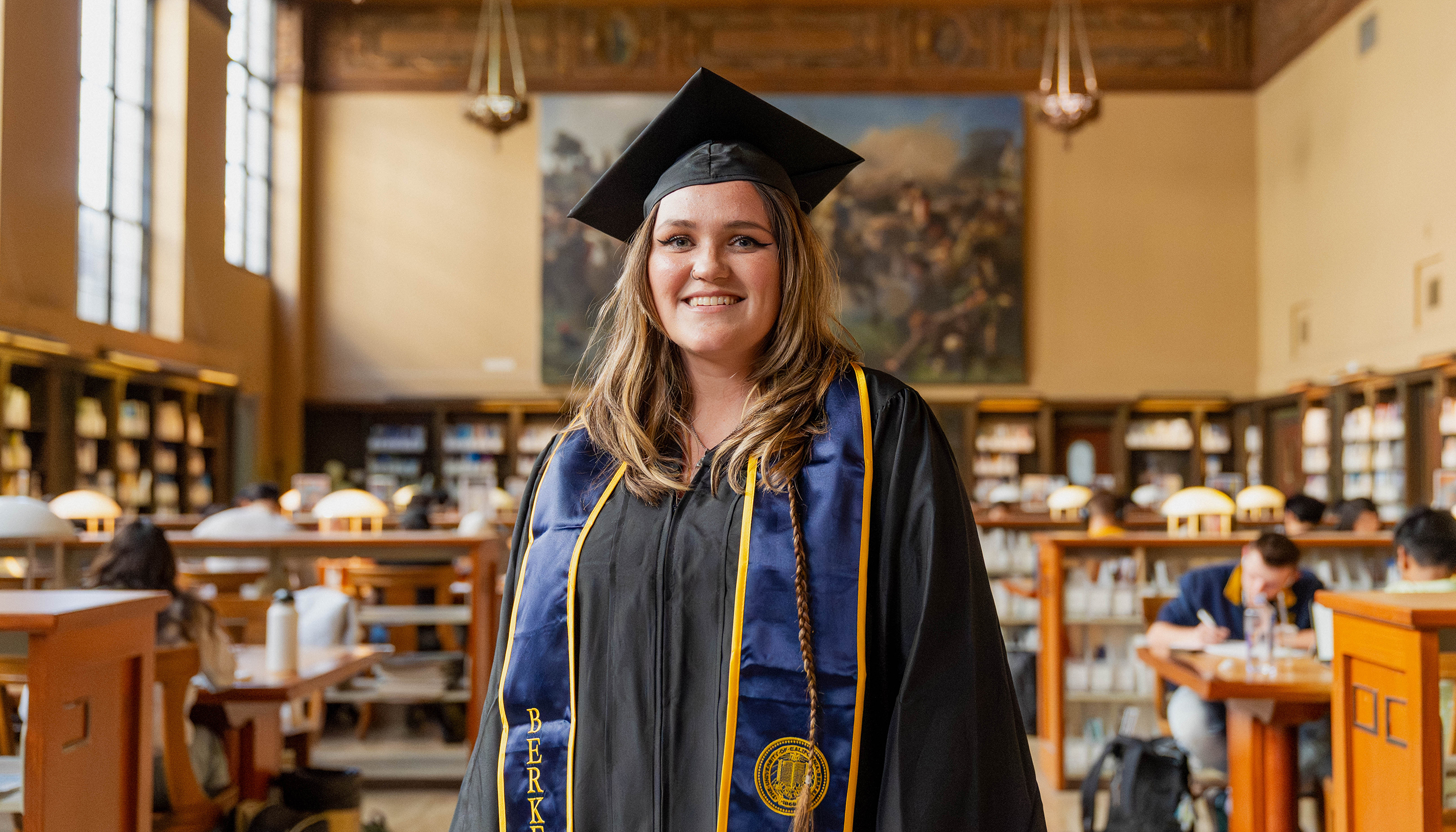 Emily Thompson in Cap and Gown in Doe Library Reading Room